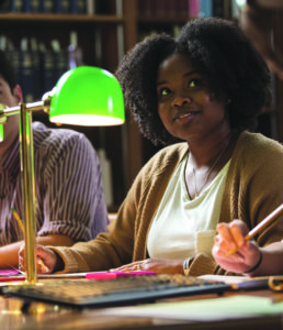 Student Life student sitting at a table with a green lamp